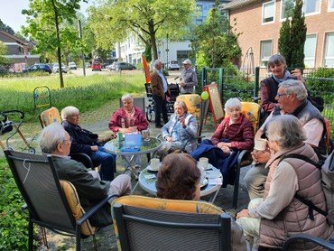 Eine Gruppe älterer Menschen sitzt draußen an einem Tisch.