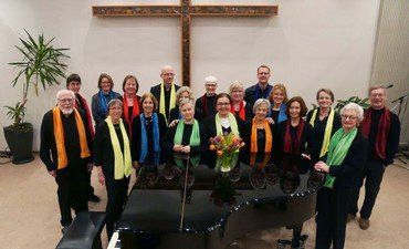 Eine Gruppe von Chormitgliedern vor einem Klavier.
