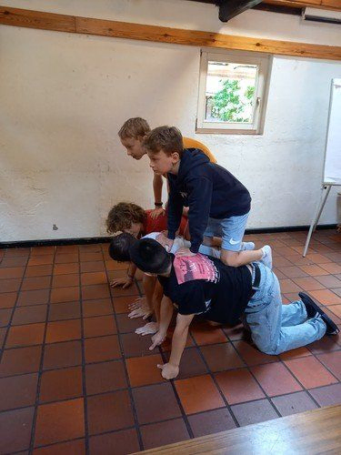 Kinder spielen ein Spiel, indem sie drinnen aufeinander stapeln.