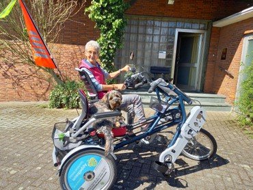 Frau mit Hund auf einem Tandem-Dreirad.