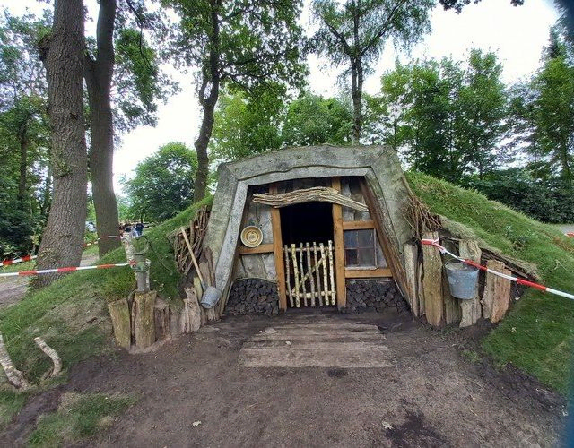 Ein Hobbit-ähnliches Torfhaus oder Erdhaus in einem Grashügel mit Bäumen.