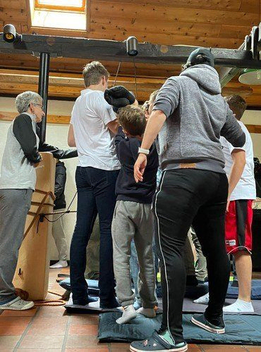 Eine Gruppe von Personen steht auf kleinen Matten und arbeitet bei einer Indoor-Aktivität zusammen.