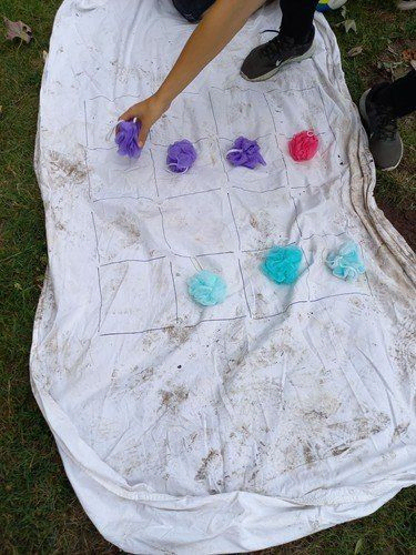 Person legt Schwämme auf Raster auf Laken im Gras.
